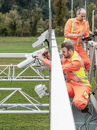 image shows EFKON engineer mounting electronic toll equipment on a gatntry