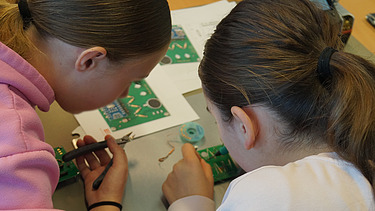 Image shows two girls focused on their work 