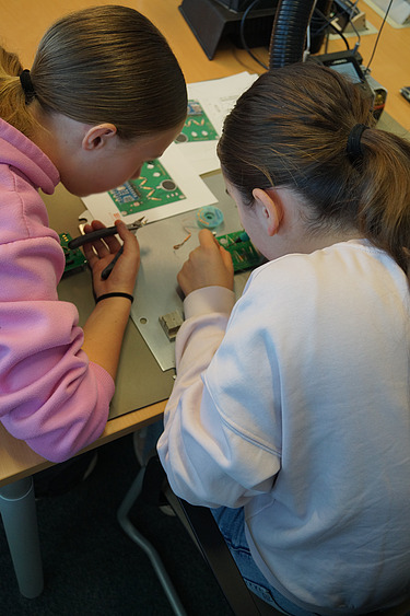 Image shows two girls focused on their work 